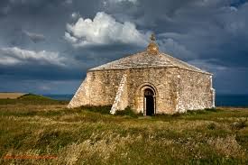 square stone built structure surrounded by grass with grey sky